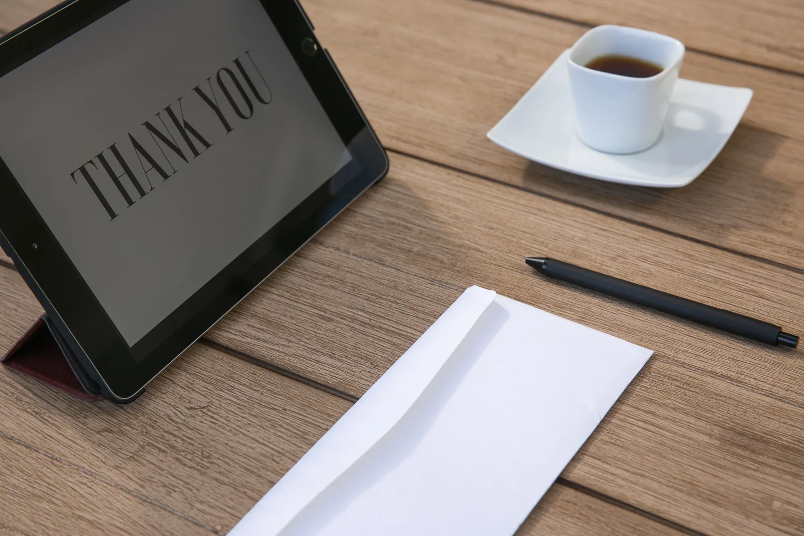 Sophisticated workspace setup with tablet displaying 'Thank You', cup of tea, pen, and envelope on wooden table. CASL for nonprofits: how consent rules change your email list