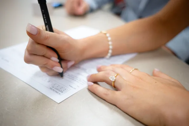 Detailed view of hands filling out a form with elegant jewelry and manicure. Who signs each line of a donor acquisition checklist